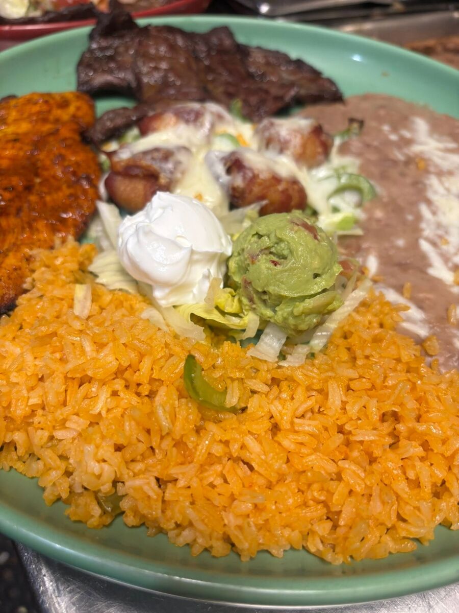 Carne asada with an enchilada, guacamole and sour cream